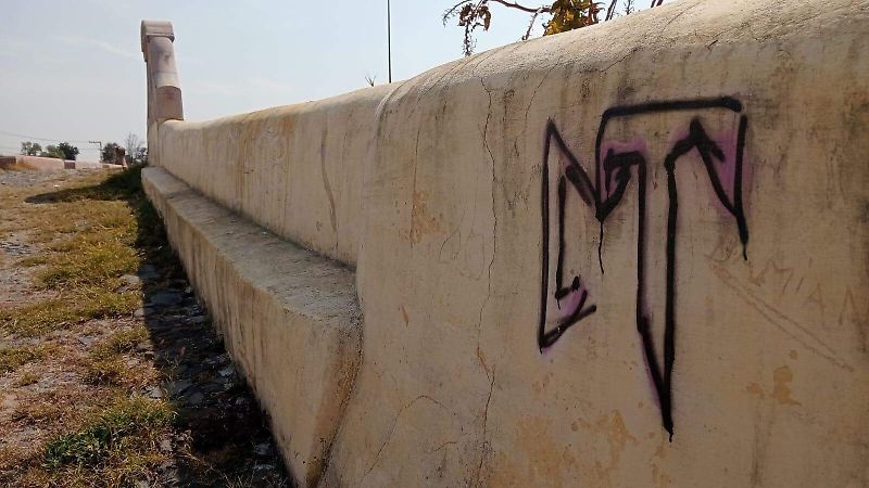 Grafiti y capas de pintura caídas muestran el abandono y desgaste del puente,